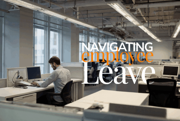 a modern office filled with people working at desks - with one desk empty. The image has the words "navigating employee leave" across it.